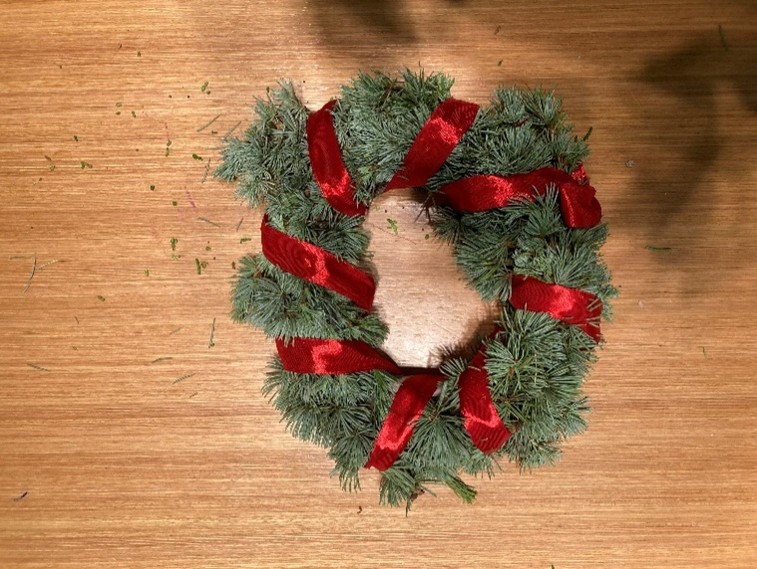 A wreath with red ribbon on a wood surface