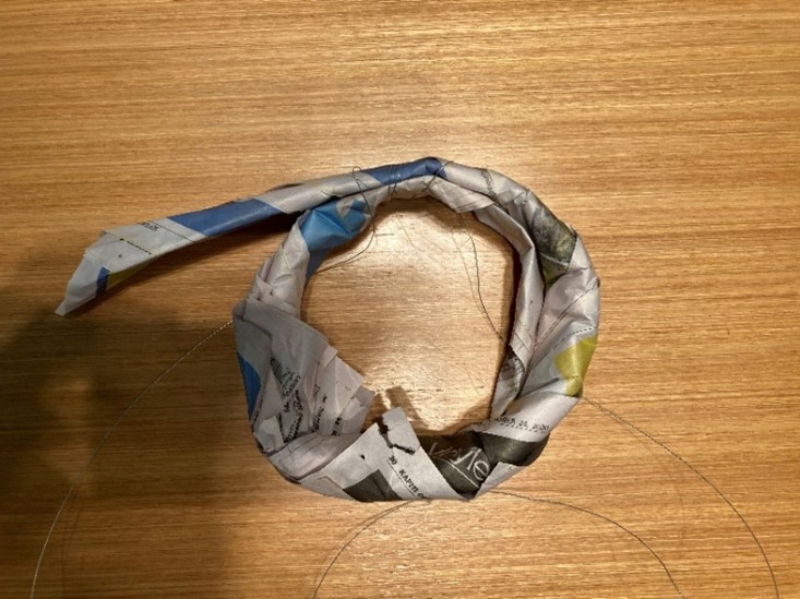 Paper formed into a ring showing how the ring will not keep shape without wire.