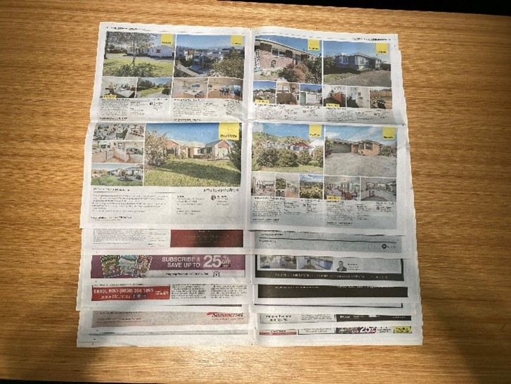 Multiple sheets of newspaper laid flat and overlapping to form a square.